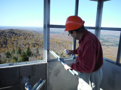 Bob spraying cold galvanization into drilled holes on window frame